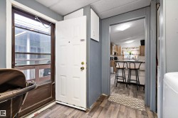 Entryway featuring a white paneled door, wood-finish flooring, and a screen door - 