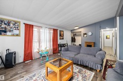 Spacious living area featuring wood-finish flooring, a vaulted ceiling, and ample natural light from multiple windows - 