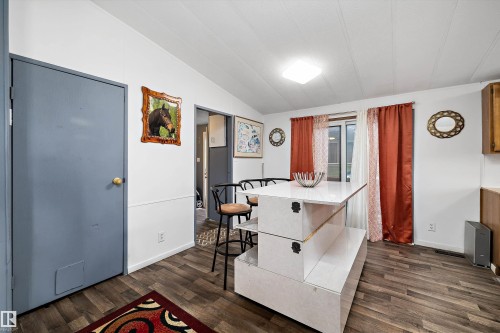 Dining room featuring wood-finish flooring, a central island with a white countertop, and a window with both sheer and opaque curtains - 46 Maple Terrace Northwest, Edmonton, AB - Indoor