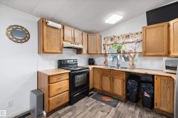 Kitchen featuring wood-finish cabinetry, a double basin sink, and a black electric range - 
