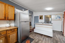 Kitchen area featuring wood-finish flooring, oak cabinetry, and a modern ceiling light fixture - 