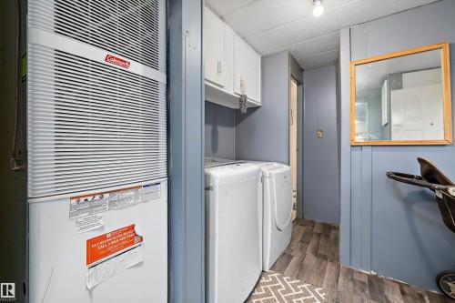 Dedicated utility area featuring a central air unit, side-by-side washer and dryer, upper cabinetry, and wood-finish flooring - 46 Maple Terrace Northwest, Edmonton, AB - Indoor Photo Showing Laundry Room