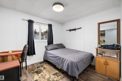 Room featuring wood-finish flooring, white paneling, and a window with dark curtains - 