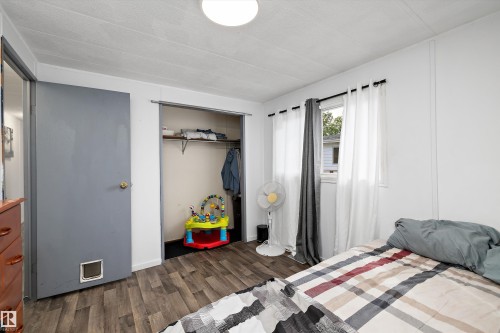 Bedroom featuring wood-finish flooring, a window with curtains, and a built-in closet with shelving and hanging rod - 46 Maple Terrace Northwest, Edmonton, AB - Indoor Photo Showing Bedroom
