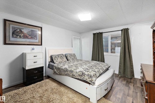 Bedroom featuring wood-finish flooring, white walls, and a window with dark drapery - 46 Maple Terrace Northwest, Edmonton, AB - Indoor Photo Showing Bedroom