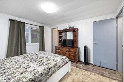 Room featuring wood-finish flooring, white walls, and a window with green curtains - 