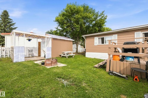 Grassed backyard with a wood deck, a covered patio structure, a freestanding shed, a picnic table, and a fire pit area - 46 Maple Terrace Northwest, Edmonton, AB - Outdoor With Exterior