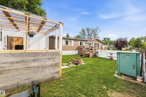 Expansive backyard featuring a manicured lawn, a built-in fire pit, and a spacious wood deck - 46 Maple Terrace Northwest, Edmonton, AB - Outdoor