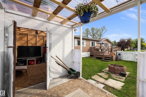 Custom built storage shed (could be used as a greenhouse) in back yard featuring a fire pit with stone pavers, and a white privacy fence - 46 Maple Terrace Northwest, Edmonton, AB - Outdoor With Exterior