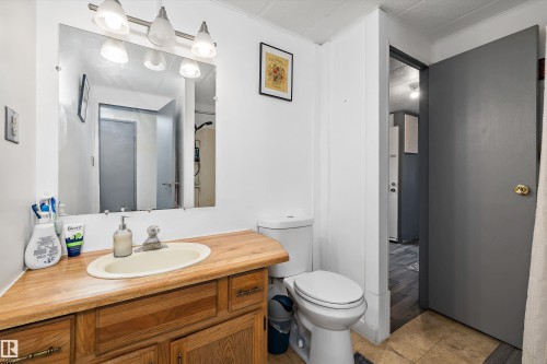Main 4 piece bathroom with a wood-finish vanity, integrated sink, and an overhead vanity light fixture - 46 Maple Terrace Northwest, Edmonton, AB - Indoor Photo Showing Bathroom