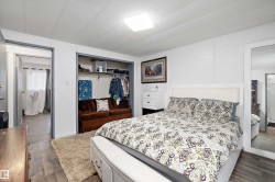 Spacious primary bedroom featuring wood-finish flooring, white paneled walls, and a recessed ceiling light - 