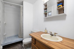 Bathroom featuring a stand-up shower, wood-finish vanity with an integrated sink, and a mirrored medicine cabinet with open shelving - 