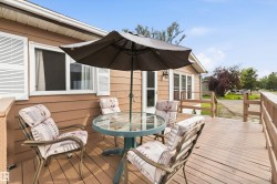 Expansive outdoor deck featuring wood-finish flooring, a wood railing, and a tan siding exterior - 