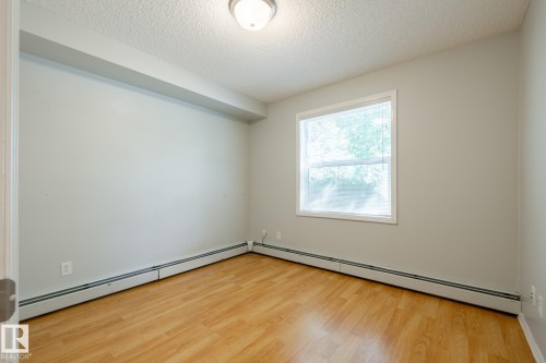 Bright interior space featuring wood-finish flooring and neutral wall tones - #103 12838 65 St Nw Nw, Edmonton, AB - Indoor Photo Showing Other Room