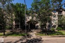 Multi-story residential building featuring a covered entryway, multiple balconies with glass railings, and a landscaped frontage with mature trees - #103 12838 65 St Nw Nw, Edmonton, AB  - Outdoor 