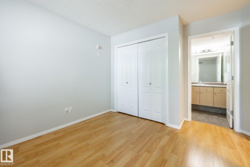 Wood-finish flooring throughout, featuring a double bifold closet - #103 12838 65 St Nw Nw, Edmonton, AB - Indoor Photo Showing Other Room