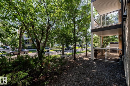 Ground-level outdoor patio featuring a gravel surface and glass panel railings - #103 12838 65 St Nw Nw, Edmonton, AB - Outdoor