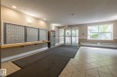 Lobby entrance featuring comprehensive mailboxes with a wood-finish ledge, neutral tone walls, and ceramic tile flooring - #103 12838 65 St Nw Nw, Edmonton, AB  - Indoor Photo Showing Other Room 