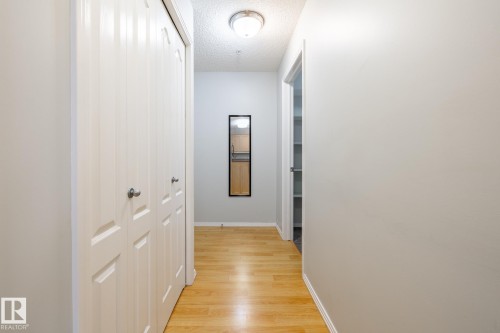 Hallway featuring wood-finish flooring, light gray walls, white trim, and a flush mount ceiling light - #103 12838 65 St Nw Nw, Edmonton, AB - Indoor Photo Showing Other Room