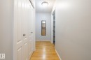 Hallway featuring wood-finish flooring, light gray walls, white trim, and a flush mount ceiling light - #103 12838 65 St Nw Nw, Edmonton, AB  - Indoor Photo Showing Other Room 