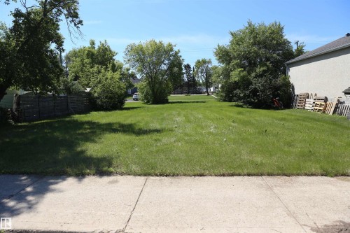 Expansive green lot featuring mature trees and a sidewalk border - 5211 53Av, Mundare, AB 