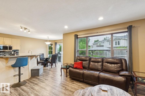 Open-concept living space featuring wood-finish flooring, recessed lighting, and a kitchen island with a breakfast bar - 16765 119 Street Nw, Edmonton, AB - Indoor
