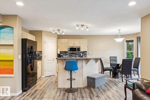 Open-concept kitchen and dining area featuring wood-finish flooring, light-toned cabinetry, a black appliance suite, a multi-tone tile backsplash, and recessed ceiling lighting - 16765 119 Street Nw, Edmonton, AB - Indoor Photo Showing Kitchen