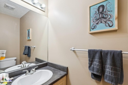 Bathroom featuring a vanity with an integrated sink, a dark countertop, a wall-mounted mirror, and overhead vanity lighting - 16765 119 Street Nw, Edmonton, AB - Indoor Photo Showing Bathroom