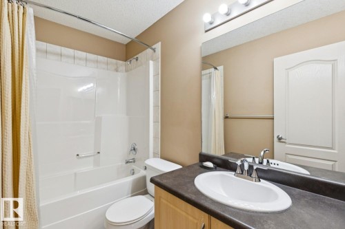 Bathroom featuring a white bathtub and shower surround with tile accent, built-in vanity with an oval sink, laminate countertop, and a large mirror - 16765 119 Street Nw, Edmonton, AB - Indoor Photo Showing Bathroom