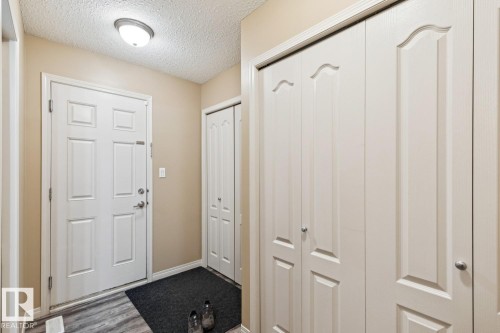 Entryway featuring a paneled door, wood-finish flooring, and multiple bi-fold storage closets - 16765 119 Street Nw, Edmonton, AB - Indoor Photo Showing Other Room