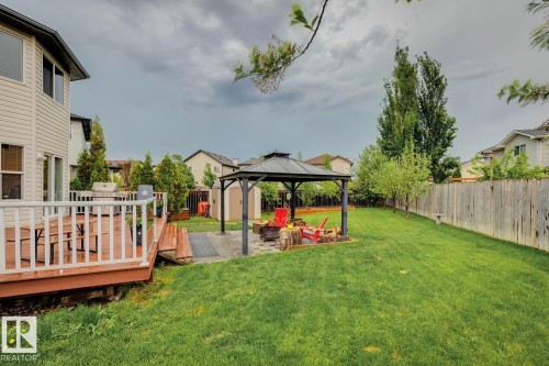 Spacious backyard featuring a multi-level wood deck, a covered patio area with pavers, a stone fire pit, and a grassy lawn framed by a wood fence - 16765 119 Street Nw, Edmonton, AB - Outdoor With Deck Patio Veranda With Backyard