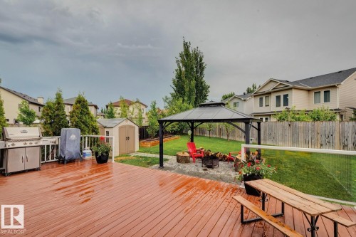 Expansive backyard featuring a stained wood deck, a metal gazebo over a paver fire pit area, a storage shed, raised garden beds, and a wood fence - 16765 119 Street Nw, Edmonton, AB - Outdoor With Deck Patio Veranda