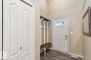 Entryway featuring wood-finish flooring, a built-in hall tree with bench and hooks, a white panel entry door with decorative glass, and a large wall-mounted mirror - 16765 119 Street Nw, Edmonton, AB  - Indoor Photo Showing Other Room 