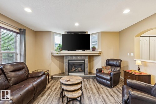 Living area featuring wood-finish flooring, recessed lighting, and a corner fireplace with a tiled surround and a mantel - 16765 119 Street Nw, Edmonton, AB - Indoor Photo Showing Living Room With Fireplace