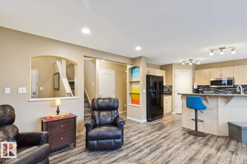 Open-concept living space featuring wood-finish flooring, recessed lighting, and an arched wall opening - 16765 119 Street Nw, Edmonton, AB - Indoor