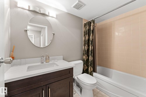 Bathroom featuring a white bathtub, light-toned wall tiles, and a vanity with a dark wood-finish cabinet - #503 10175 114 St Nw, Edmonton, AB - Indoor Photo Showing Bathroom
