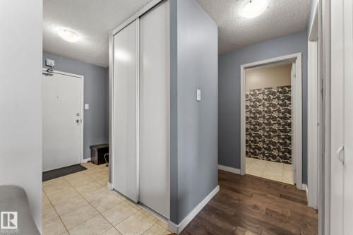 Entryway featuring light tile flooring, a built-in sliding door closet, and a wood-finish floor hallway - #503 10175 114 St Nw, Edmonton, AB - Indoor Photo Showing Other Room