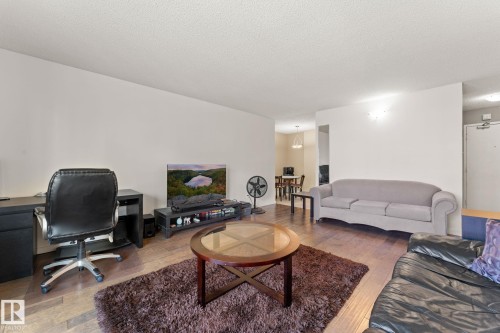 Open-concept living area featuring wood-finish flooring and neutral wall tones - #503 10175 114 St Nw, Edmonton, AB - Indoor Photo Showing Living Room