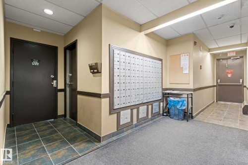 Entryway featuring a wall-mounted mailbox system, recessed and fluorescent lighting, and a combination of tile and carpet flooring - #503 10175 114 St Nw, Edmonton, AB - Indoor Photo Showing Other Room