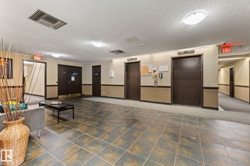 Spacious common area featuring durable tile flooring, recessed ceiling lighting, and two substantial elevator doors - #503 10175 114 St Nw, Edmonton, AB - Indoor Photo Showing Other Room