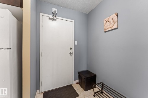 Entryway featuring a white solid door with a deadbolt and peephole, light gray wall paint, and cream-toned tiled flooring - #503 10175 114 St Nw, Edmonton, AB - Indoor Photo Showing Other Room