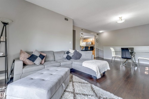 Open-concept living area featuring wood-finish flooring, recessed lighting, and a neutral color palette - #102 3040 Spence Wd Sw, Edmonton, AB - Indoor Photo Showing Living Room