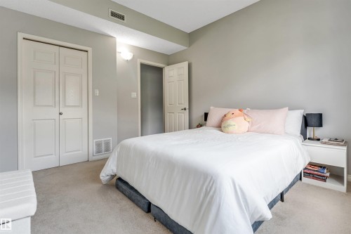 Carpeted bedroom with neutral wall tones and a white bi-fold closet - #102 3040 Spence Wd Sw, Edmonton, AB - Indoor Photo Showing Bedroom