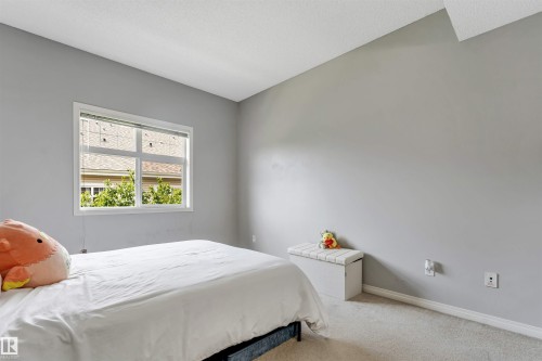 Neutral-toned bedroom featuring a white-framed window with blinds, light gray wall paint, and light-colored carpeting - #102 3040 Spence Wd Sw, Edmonton, AB - Indoor Photo Showing Bedroom