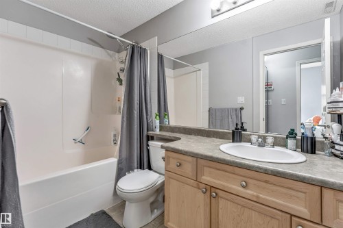 Bathroom featuring a vanity with light wood cabinetry, a composite countertop, and an oval undermount sink - #102 3040 Spence Wd Sw, Edmonton, AB - Indoor Photo Showing Bathroom