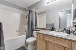 Bathroom featuring a vanity with light wood cabinetry, a composite countertop, and an oval undermount sink - 