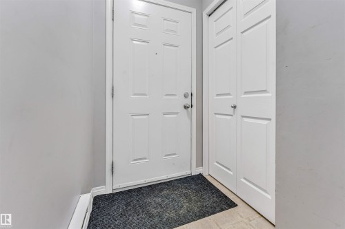 Entryway featuring a paneled door with polished chrome hardware, light gray walls, and light-toned flooring - #102 3040 Spence Wd Sw, Edmonton, AB - Indoor Photo Showing Other Room
