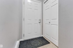 Entryway featuring a paneled door with polished chrome hardware, light gray walls, and light-toned flooring - 