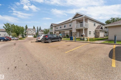 Residential building with light-colored siding and stone accents - #102 3040 Spence Wd Sw, Edmonton, AB - Outdoor With Balcony