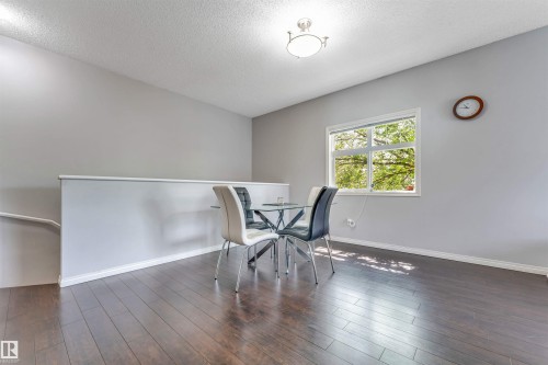 Open concept upper level featuring dark wood-finish flooring, a contemporary ceiling light fixture, and a window with white trim - #102 3040 Spence Wd Sw, Edmonton, AB - Indoor Photo Showing Other Room